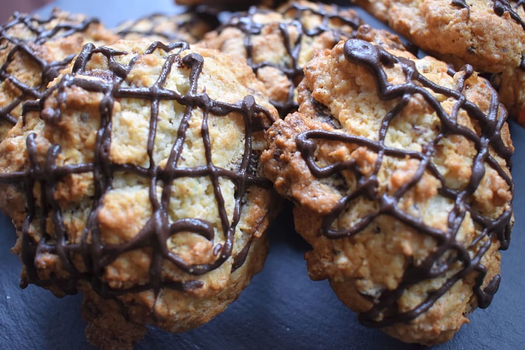 Two Coconut, Cherry and Chocolate Rock Buns on a black board.
